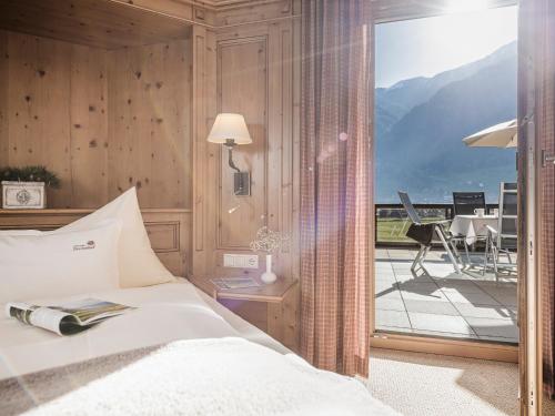 a bedroom with a bed and a view of a balcony at Aparthotel Stacherhof in Fügen
