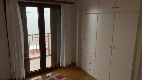 a room with a large window and white cabinets at Ξύλο & Παράδοση in Pávliani