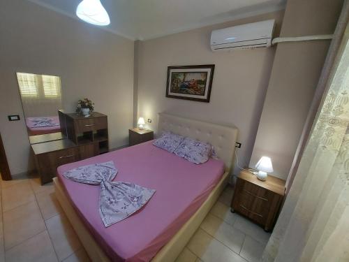 Dormitorio pequeño con cama rosa y espejo en Bral Apartments, en Durrës