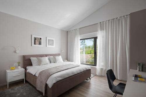 a white bedroom with a large bed and a window at Villa Artemis in Sveti Petar u Šumi