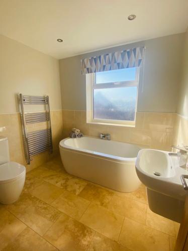 a bathroom with a tub and a sink and a window at Acacia Breezes - Delightful Scarborough Semi in Scarborough