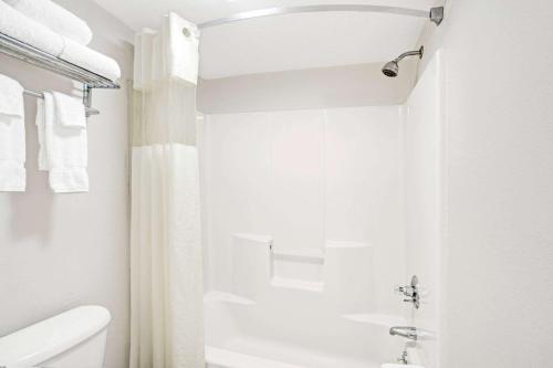 a white bathroom with a shower and a toilet at Travelodge by Wyndham Suites St Augustine in Saint Augustine