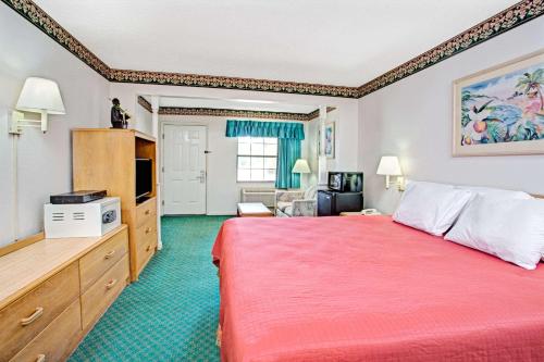 a hotel room with a red bed and a living room at Travelodge by Wyndham Suites St Augustine in St. Augustine