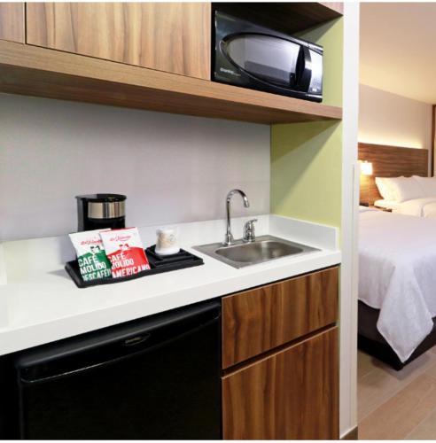 a kitchen with a sink and a bed in a room at Holiday Inn Express & Suites - Playa del Carmen by IHG in Playa del Carmen