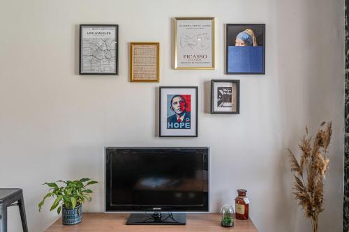 een flatscreen-tv op een bureau met foto's aan de muur bij Chez Côme in Metz