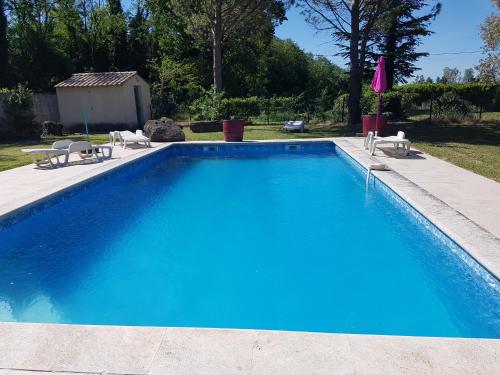 a blue swimming pool with two chairs and a umbrella at Les Buisses en Provence in Piolenc