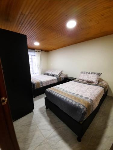 a bedroom with two beds and a wooden ceiling at Cabaña Campestre Katie in Paipa