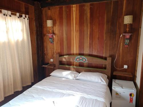 a bedroom with a bed with a wooden wall at Chalé de madeira in Santa Cruz de Minas