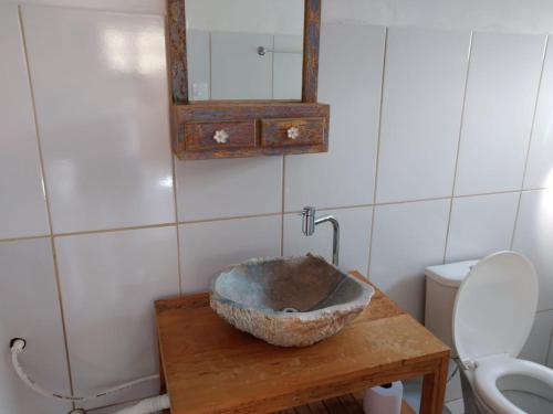 a bathroom with a bowl on a table with a toilet at Chalé de madeira in Santa Cruz de Minas