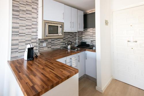 a kitchen with white cabinets and a wooden counter top at Dream Studio in Benalmadena Costa del Sol in Benalmádena