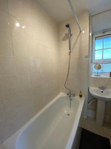 a white bathroom with a tub and a sink at London Waterloo Apartment in London