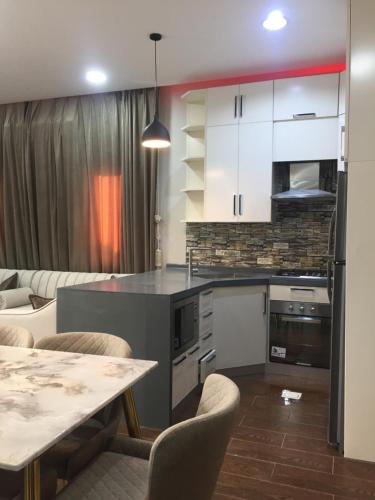 a kitchen with white cabinets and a table with chairs at شاليه ابها ون in Al ‘Az̧āz̧ah