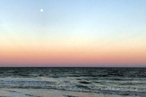 a sunset over the ocean with the moon in the sky at Beckenham in Hilton Head Island