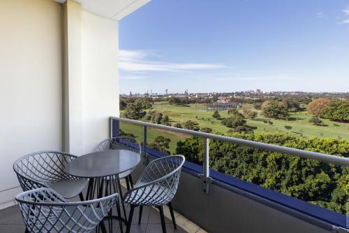 a balcony with a table and chairs and a view at Meriton Suites Waterloo in Sydney