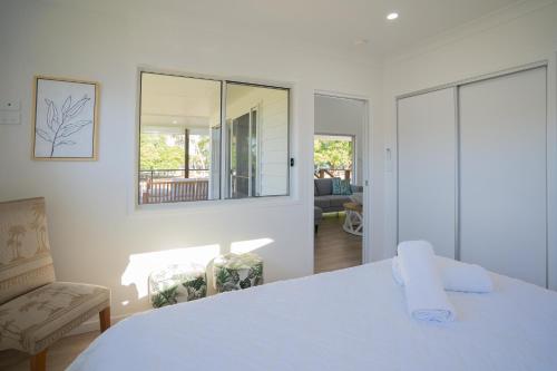 Habitación blanca con cama y espejo en Crab Cottages, en Urangan
