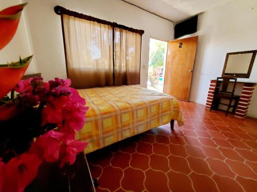 Hotel Oasis Melaque في سان باتريسيو ميلاكي: غرفة نوم بسرير وزهور في غرفة