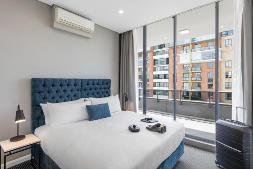 a hotel room with a bed and a large window at Meriton Suites Waterloo in Sydney
