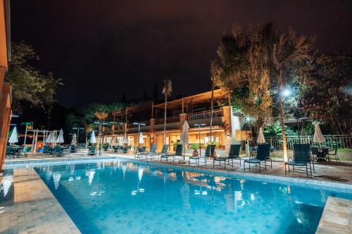 a swimming pool at night with chairs and umbrellas at Hotel Pousada do Bosque in Ponta Porã