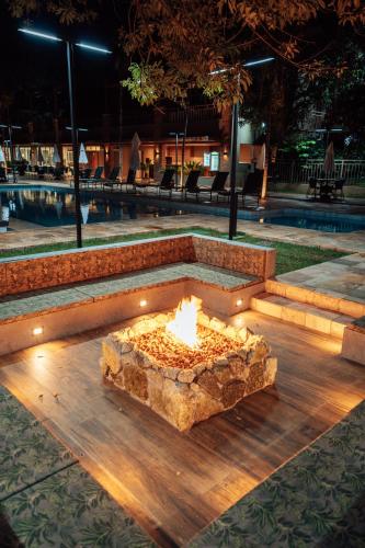 a fire pit in front of a pool at night at Hotel Pousada do Bosque in Ponta Porã