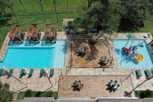 an overhead view of a swimming pool with people sitting around it at Hotel Pousada do Bosque in Ponta Porã