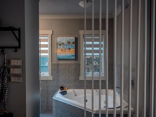 ein Badezimmer mit einer Badewanne und zwei Fenstern in der Unterkunft Sailaway Beach House in Seaford