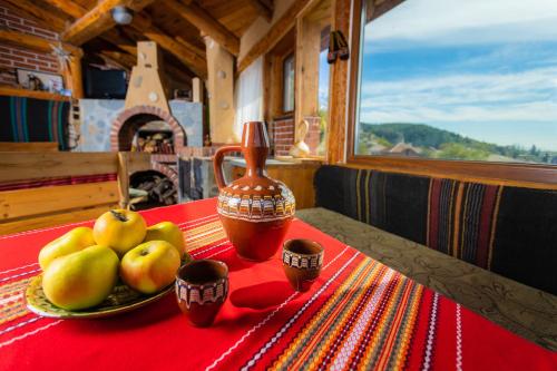 uma mesa com um prato de maçãs e um vaso sobre ela em Eco Village Under the Cliffs em Ilindentsi