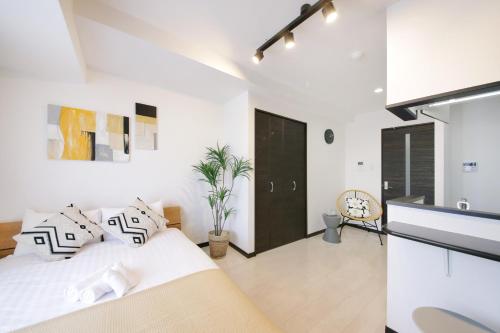 a white bedroom with a bed and a black door at Green Sea Oshiage in Tokyo
