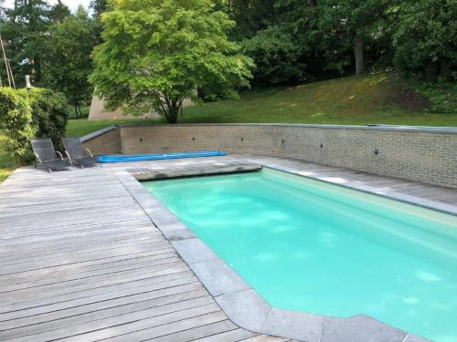 einen Pool mit 2 Stühlen und eine Holzterrasse in der Unterkunft Picturesque villa in Bierges with swimming pool and barbeque in Bierges