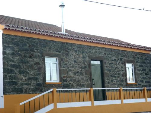 a stone house with a wooden fence in front of it at Charming green country house in Laseira