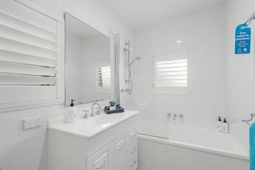 a white bathroom with a tub and a sink at Casa Sorella - beachfront family home with pool in North Haven