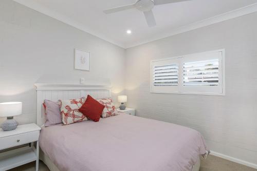 a white bedroom with a bed and a window at Casa Sorella - beachfront family home with pool in North Haven