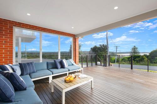 a living room with a blue couch on a balcony at Casa Sorella - beachfront family home with pool in North Haven