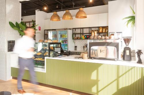 a man walking past a counter in a bakery at Oaks R Suites Geelong in Geelong