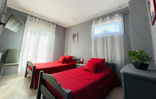 two beds in a room with red sheets and a window at L organdi in Cornebarrieu
