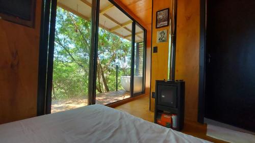 um quarto com uma cama e uma grande janela de vidro em Casa da Árvore espaço Vila da Serra em Nova Lima