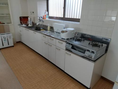 a white kitchen with a stove and a sink at Yatsugatake Cottage in Hokuto