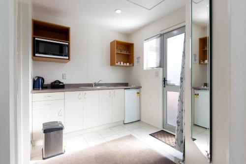a kitchen with white cabinets and a sink at Riccarton Motor Lodge in Christchurch