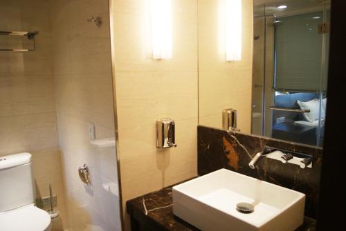 a bathroom with a sink and a toilet and a mirror at Nanjing Kaibin Apartment -Xin Jie Kou in Nanjing