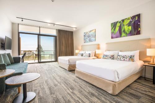 Habitación de hotel con 2 camas y sofá en Narrabeen Sands Hotel by Nightcap Plus, en Narrabeen