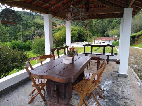 einen Holztisch und Stühle auf einer Terrasse in der Unterkunft Pousada Pedacinho do Ceu- chalé 1 in Cunha