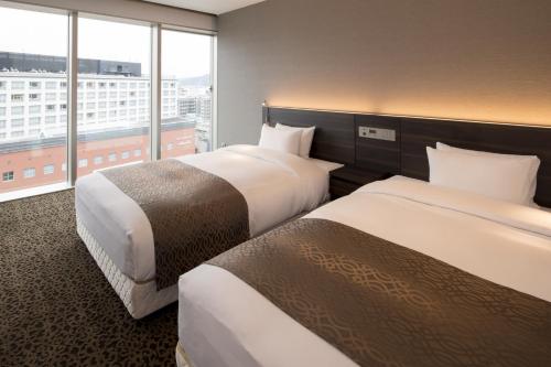 a hotel room with two beds and a large window at Piazza Hotel Nara in Nara