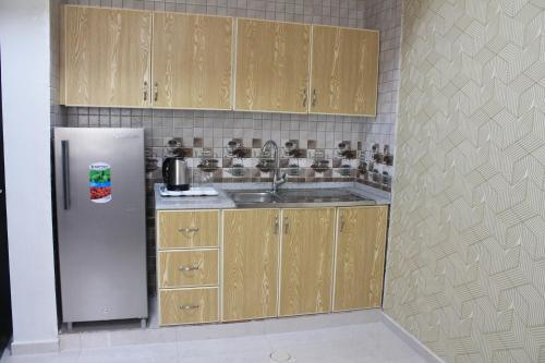 a kitchen with wooden cabinets and a stainless steel refrigerator at AL MARSA HOTEL APARTMENTS in Khor Fakkan