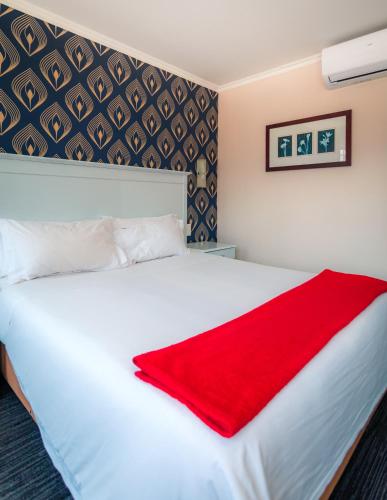 a bedroom with a large white bed with a red blanket at Florida Park Hotel, Florida Road in Durban