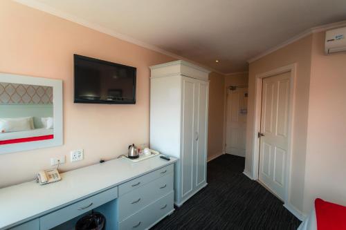a bedroom with a dresser with a television on the wall at Florida Park Hotel, Florida Road in Durban