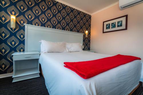 a bedroom with a white bed with a red blanket on it at Florida Park Hotel, Florida Road in Durban