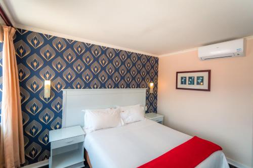 a small bedroom with a white bed and a blue wall at Florida Park Hotel, Florida Road in Durban