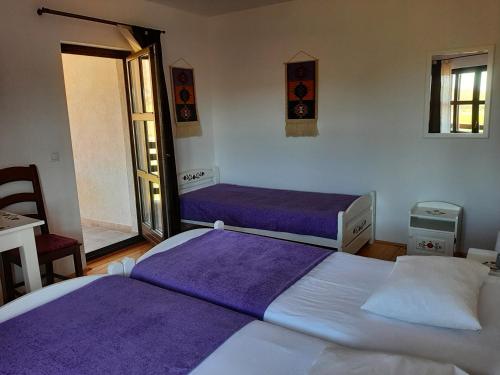 - 2 lits dans une chambre avec des draps violets dans l'établissement Pensiunea Marceluca, à Hodoşa