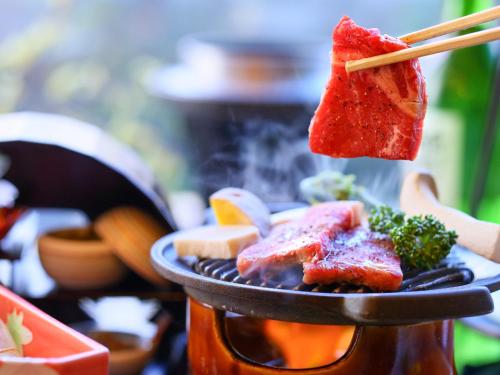a person holding a piece of food on a plate at Jizaiso in Nasu