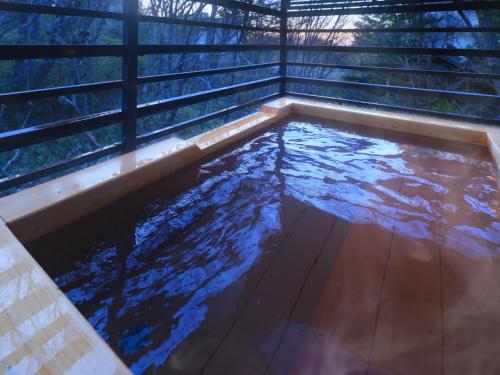 a pool of water in a tub with trees in the background at Jizaiso in Nasu