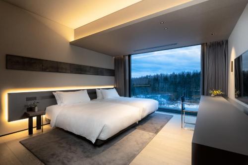 sypialnia z dużym łóżkiem i dużym oknem w obiekcie Sansui Niseko w mieście Kutchan